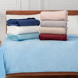 A collection of soft, folded fleece blankets in various colors including navy, white, light blue, pink, gray, beige, and burgundy, displayed on a bed with a light blue blanket spread out.