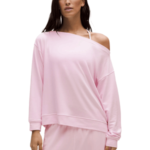 A person is wearing a light pink, off-shoulder, long-sleeve top with casual styling, paired with matching bottoms.