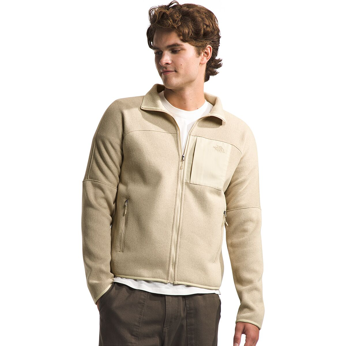 A man wearing a light beige fleece jacket with a stand-up collar and zippered pockets.