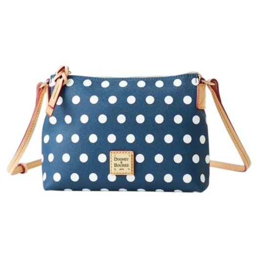 A polka dot crossbody bag with a blue background and white dots, featuring a Dooney & Bourke label and beige adjustable straps.