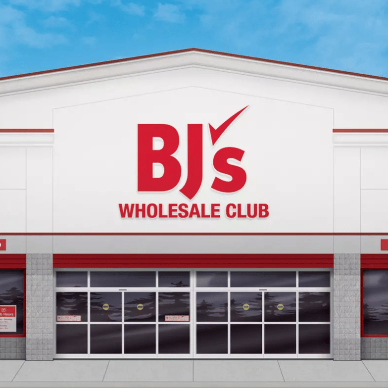 BJ's Wholesale Club storefront featuring signs for curbside pickup and a spirits shop, set against a clear blue sky.