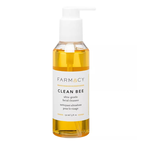 A transparent bottle with a white pump labeled \“FARMACY CLEAN BEE ultra-gentle facial cleanser\“ filled with a yellow liquid, designed for skincare.