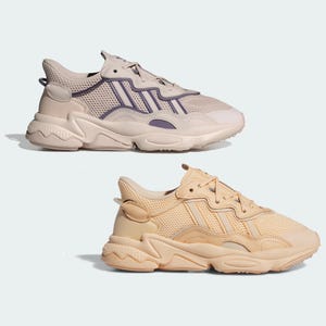 Two pairs of athletic sneakers, one in light beige with purple accents on top and the other in a solid creamy beige color below.