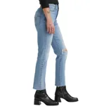 A person is wearing light blue ripped jeans paired with black ankle boots with a block heel.