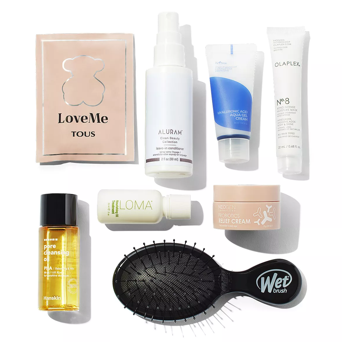 The set includes a Tous LoveMe perfume sachet, Aluram leave-in conditioner, Hyaluronic Acid Aqua Gel Cream, Olaplex No. 8 Bond Intense Moisture Mask, Hanskin Pore Cleansing Oil, Loma shampoo, Neogen Probiotics Relief Cream, and a Wet Brush.