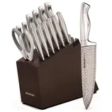 A knife set in a wooden block includes multiple stainless steel knives and kitchen shears. The visible chef's knife has a textured blade and is branded with \“AsterCook.\“
