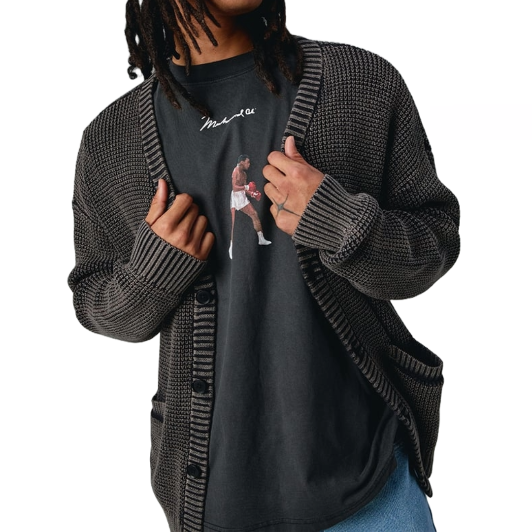 A black knit cardigan sweater with large ribbed cuffs and hem, button closure, and front pockets, worn over a graphic t-shirt featuring a boxer.