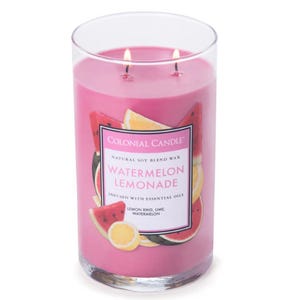 A pink Watermelon Lemonade candle by Colonial Candle, featuring a natural soy blend wax and infused with essential oils including lemon rind, lime, and watermelon. The glass jar has two wicks.