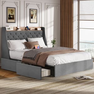 A gray upholstered bed with a tufted headboard features built-in storage drawers and shelving. It is dressed with white and brown bedding, and is set in a room with elegant wall decor, brown curtains, and natural light.