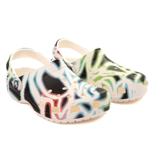 Glow-in-the-dark Crocs with vibrant, multicolored graffiti-like patterns, featuring holes for breathability and a back strap for secure fit.