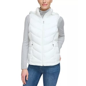 A white packable hooded puffer vest featuring a front zipper, two zippered pockets, and chevron quilting. It's worn over a light gray long-sleeve shirt and paired with blue jeans.