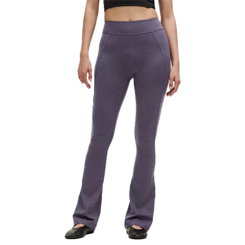 Woman wearing high-waisted, purple flare leggings paired with a black crop top and black shoes.