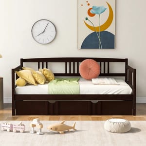 A dark wooden daybed with slatted back and side rails features storage drawers underneath. It is styled with colorful pillows and set against a wall with a clock and abstract art. A rug with wooden toys is placed in front.