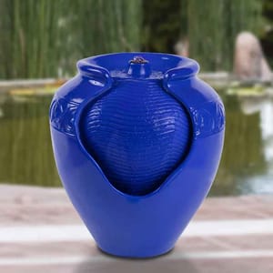 A blue ceramic vase featuring a unique design with a central textured element and open sides, placed against a blurred outdoor background.