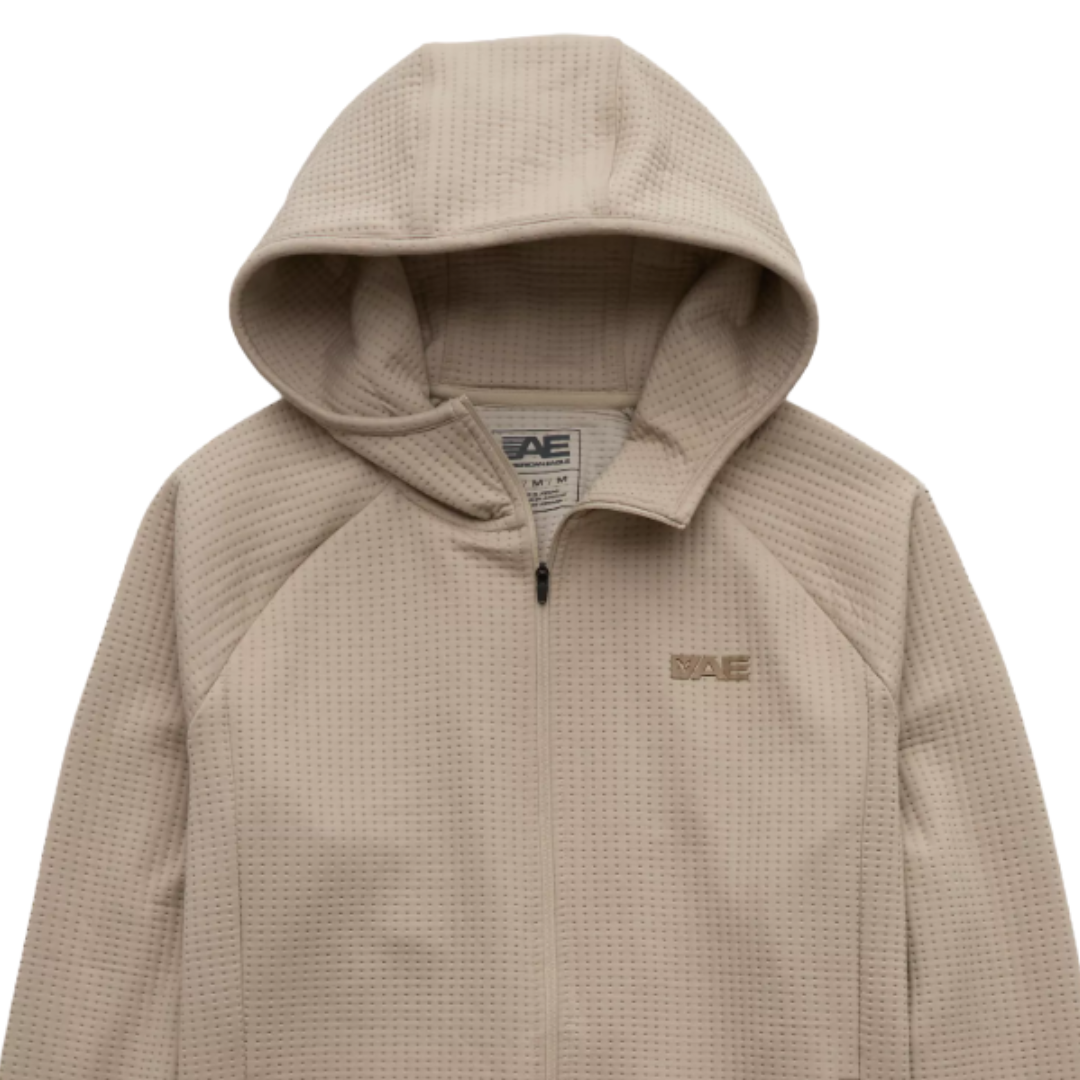 Beige hooded jacket with a textured, perforated design, featuring a front zipper and an \“AE\“ logo on the chest.
