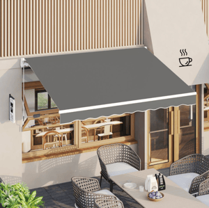 8' retractable sun shade with a grey fabric and white trim, mounted above a café window, providing shade for the outdoor seating area with wicker chairs and a table.