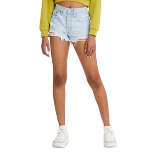 Light denim high-waisted distressed shorts with frayed hems, paired with white sneakers and a long-sleeve green top.