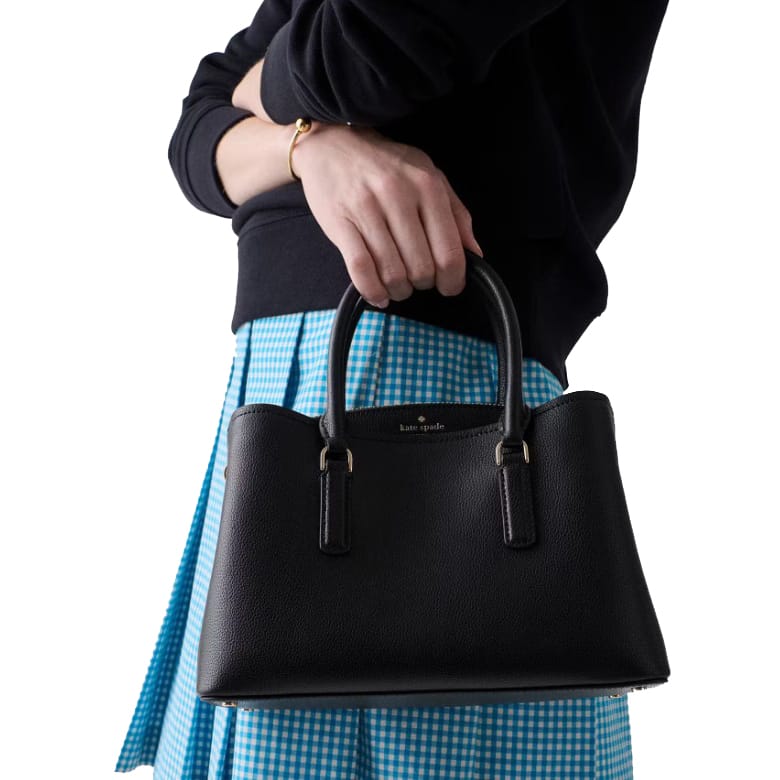 Black Kate Spade handbag with dual handles, paired with a blue gingham skirt and a black sweater.
