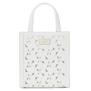 White handbag with floral cutout design and a small \“Kate Spade New York\“ label on the front.