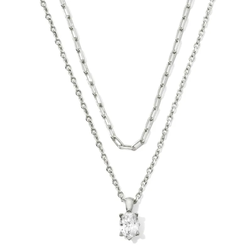 Kendra Scott multi-strand necklace features two silver chains, one with an elongated link design and the other with a smaller chain holding a clear oval gemstone pendant.