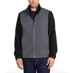 A man is wearing a gray softshell vest over a black long-sleeve shirt and dark jeans.