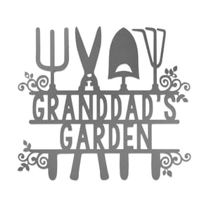 Metal sign featuring gardening tools and the text \“Granddad's Garden,\“ designed with decorative leaf and swirl accents.