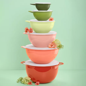 A stack of colorful food storage containers ranging from red to green, with floral accents, each with a lid, set against a green background.