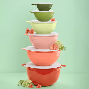 A stack of colorful food storage containers ranging from red to green, with floral accents, each with a lid, set against a green background.