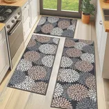 Three geometric-patterned kitchen mats feature a floral design with shades of white, beige, and gray against a dark background, placed on a light wood floor.