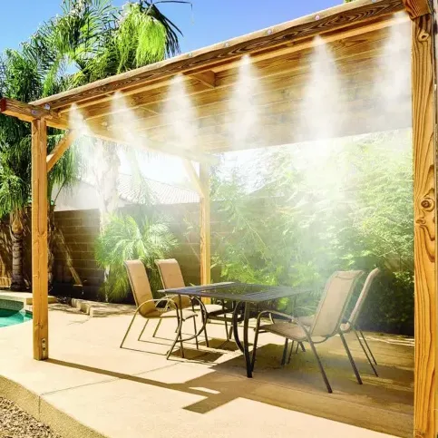 A wooden pergola with a misting system installed, positioned over a patio area with a table and chairs, near a swimming pool.