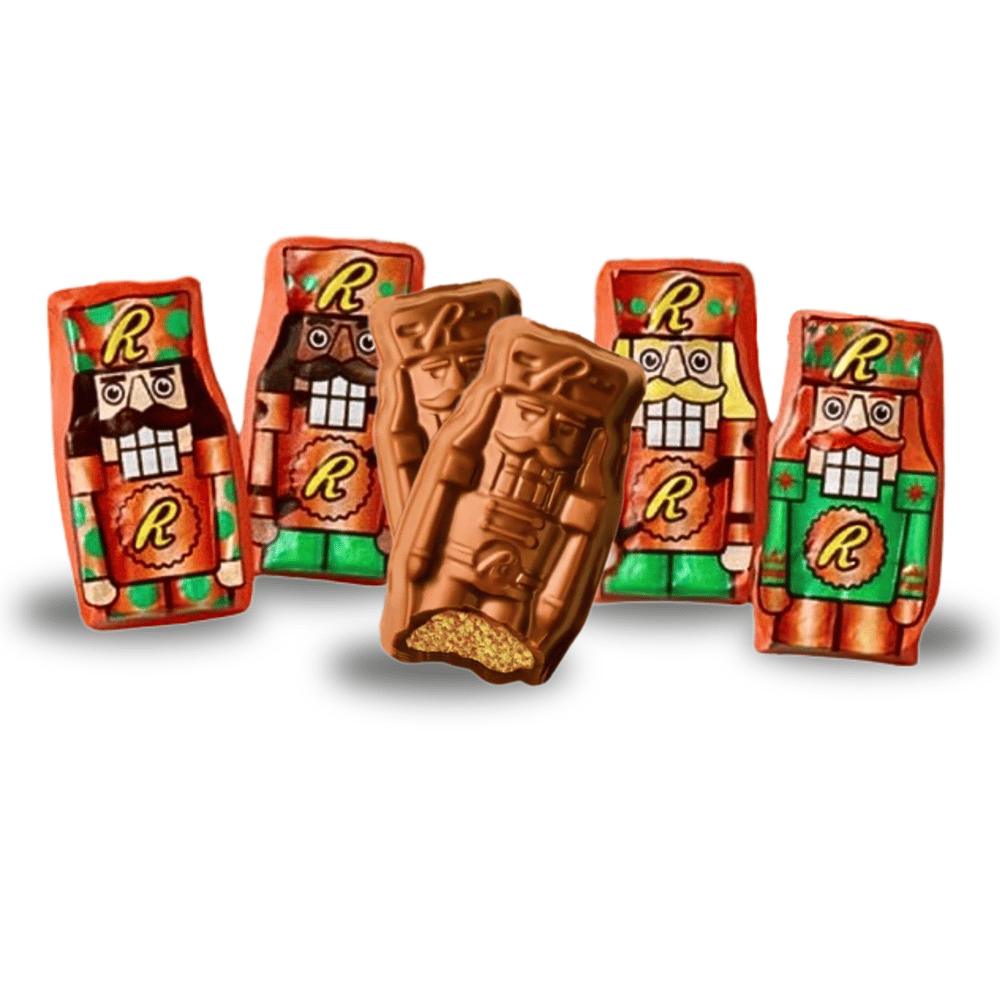 Five chocolate bars shaped and wrapped as nutcrackers with colorful foil packaging featuring an \“R\“ logo. Two bars are unwrapped, one with a bite taken, showing a creamy, textured filling.