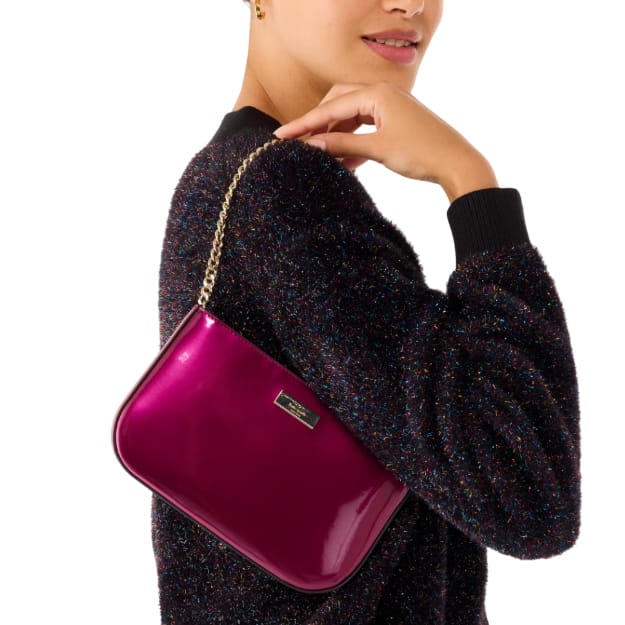 Magenta patent leather pochette with a gold chain strap, featuring a small rectangular Kate Spade logo on the front.
