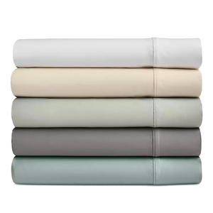 A stack of five folded bedsheets in various neutral tones, including white, beige, light gray, dark gray, and light blue.