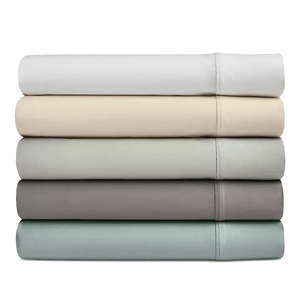 A stack of five folded bedsheets in various neutral tones, including white, beige, light gray, dark gray, and light blue.