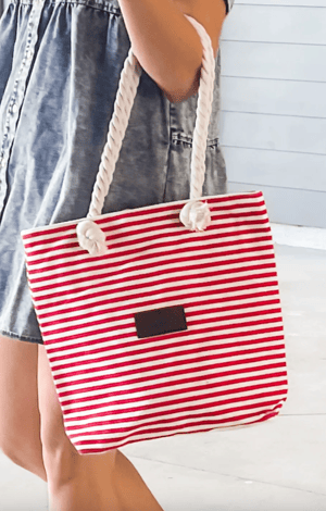 Red and white striped canvas tote bag with rope handles and a small rectangular patch on the front.
