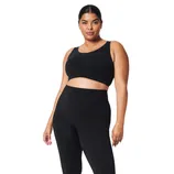 A person is wearing a sleeveless black crop top and black leggings with slits at the ankles, paired with white sneakers.