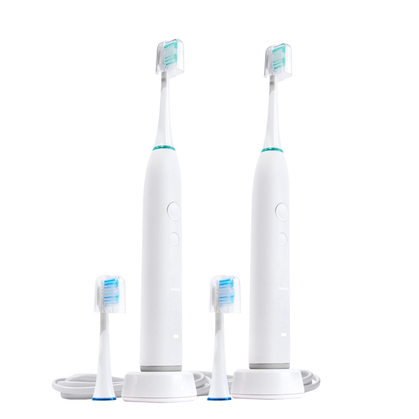 Two electric toothbrushes with their charging base and four replaceable brush heads.