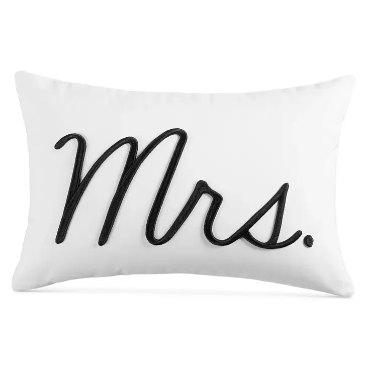 A white rectangular pillow with \“Mrs\“ written in black cursive script.