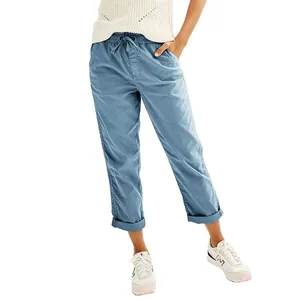 A person is wearing light blue, relaxed-fit, cuffed ankle-length pants with a drawstring waist, paired with a white knit top and white sneakers.