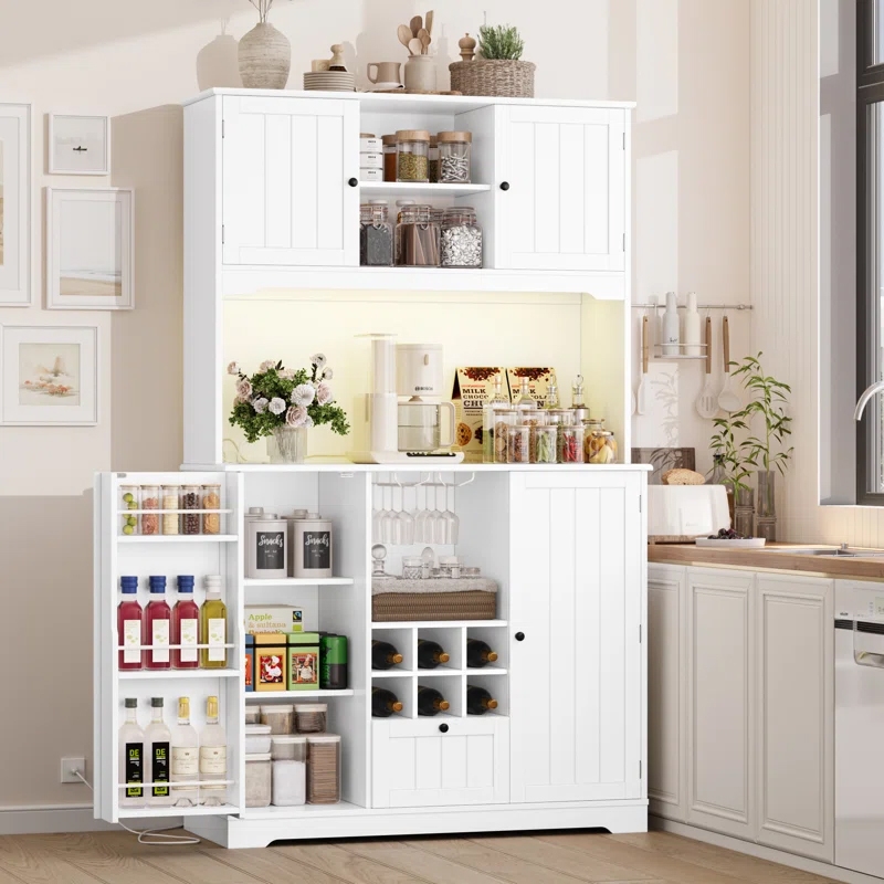 A white 71\“ kitchen pantry features LED lights, multiple storage compartments, wine racks, glass holders, and shelves for jars, spices, and beverages. It includes upper and lower cabinets, a countertop area, and decorative elements like vases and plants.