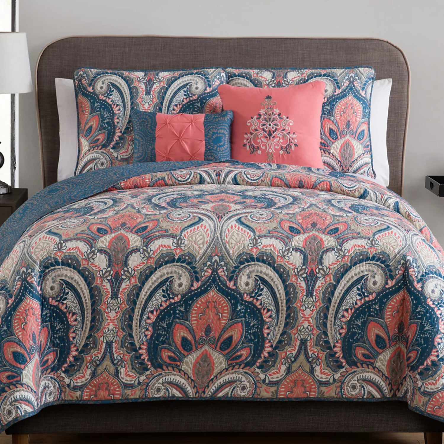 The 5pc VCNY Reversible Queen Quilt Set features a paisley pattern in pink, blue, and gray colors. It includes a quilt, two shams, and two decorative pillows, providing a stylish and coordinated look for a bedroom.