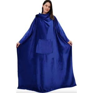 A person is wearing a royal blue, floor-length wearable blanket with a hood and a large front pocket.