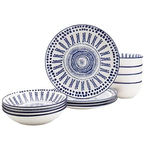 A set of blue and white patterned ceramic dinnerware, including four plates, four bowls, and four mugs. The design features intricate circular and linear patterns.