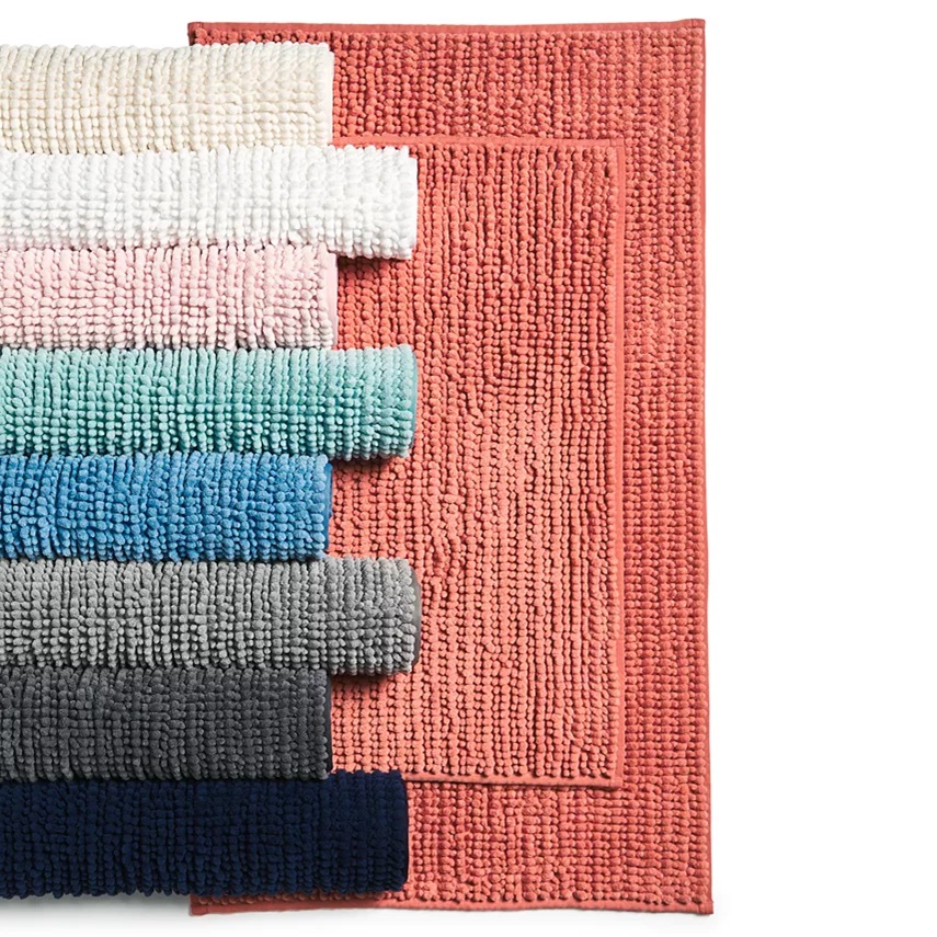 Assorted colorful bath mats stacked on top of each other.