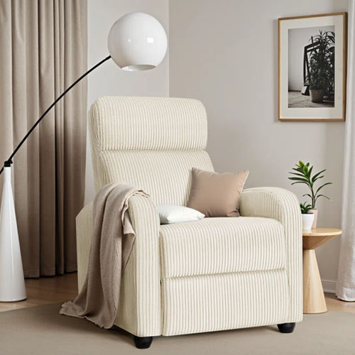 Cream-colored corduroy massage recliner with a high back, accompanied by a beige throw and a pillow, set next to a round side table and a modern floor lamp, in a neutral-toned room.