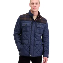 A man is wearing a navy blue quilted jacket with buttoned pockets and plaid detailing on the shoulders.