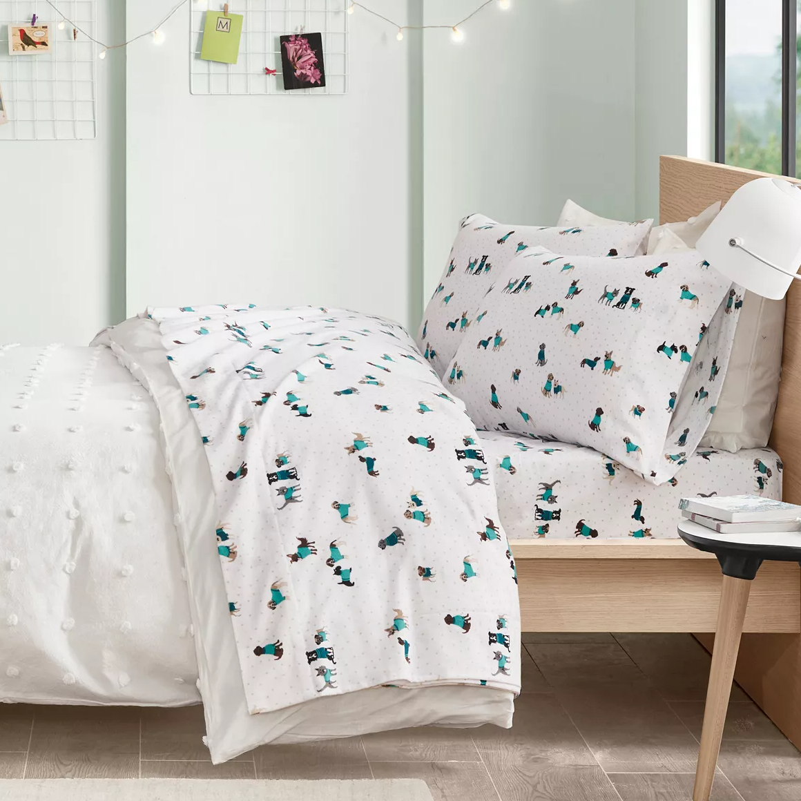 A bed with patterned bedding, featuring a white base with small cactus print, and a complementary white throw with raised pom-pom details.