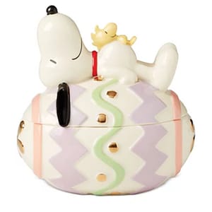 Ceramic container featuring a character lying on a pastel-colored egg with zigzag patterns and golden accents.