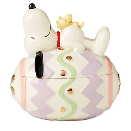 Ceramic container featuring a character lying on a pastel-colored egg with zigzag patterns and golden accents.