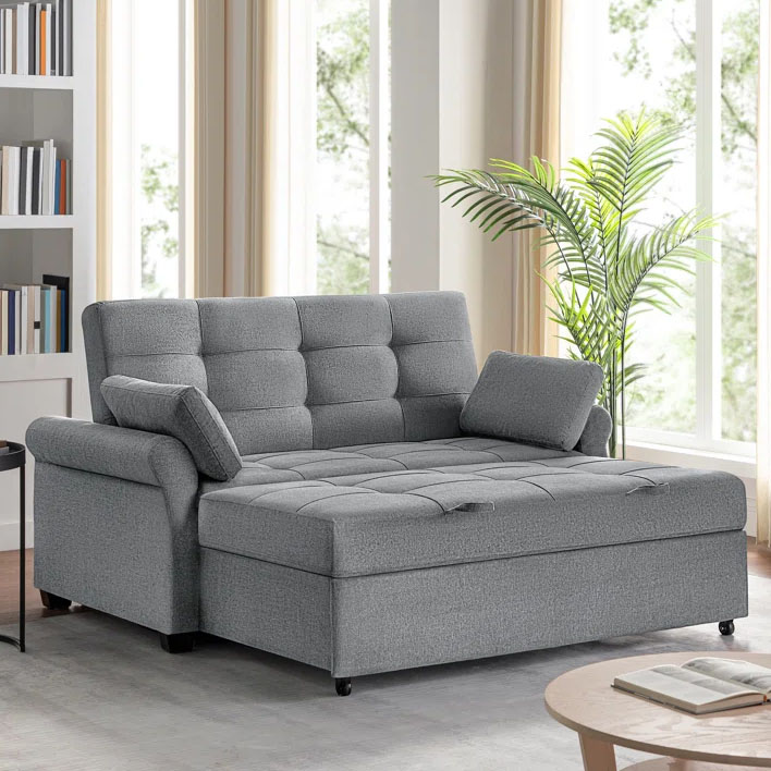 A gray Serta convertible sleeper sofa with a tufted cushion design, adjustable backrest, and one armrest cushion is positioned in a bright room beside a plant.